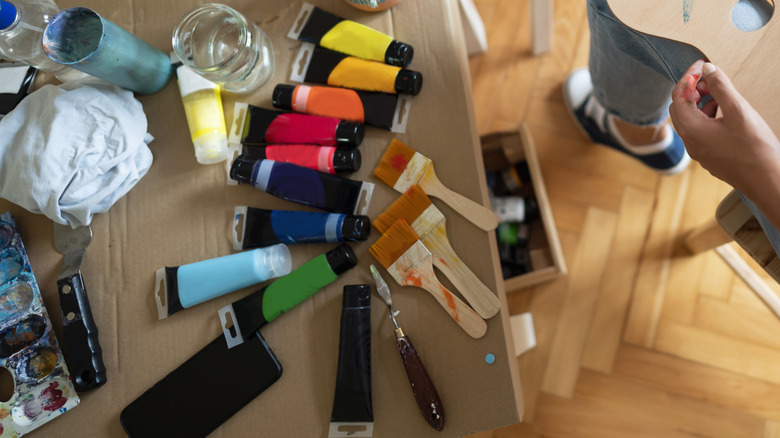 several paint tubes and supplies on a messy craft table