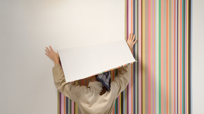 A person uses striped colorful wallpaper on white walls