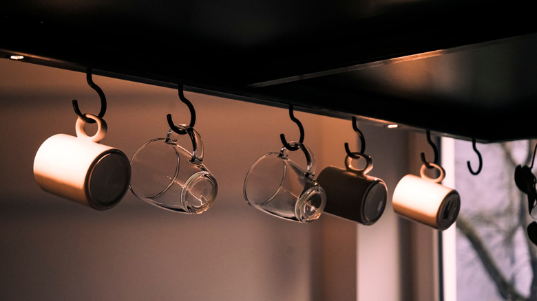 Coffee mugs hanging from cup hooks in a kitchen