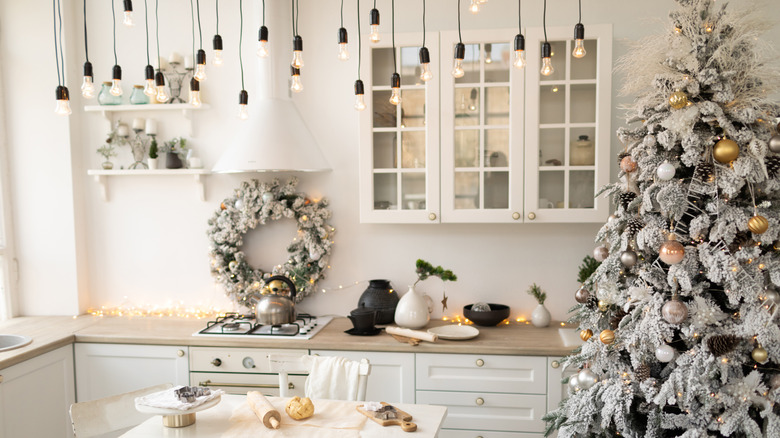 White kitchen with black accents decorated for Christmas with a Christmas tree and flocked wreath