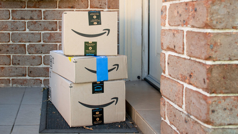 A stack of Amazon boxes on a front porch.