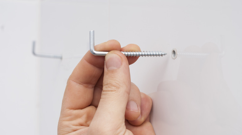 Person holding hook to wall