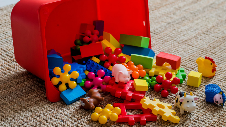 Red toy box spilling toys out onto floor