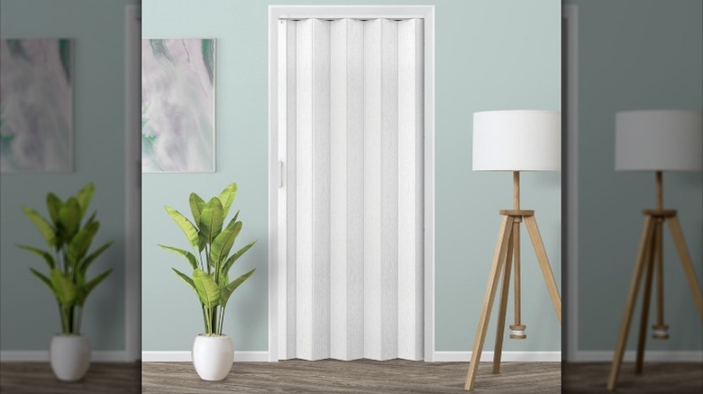 An accordion door installed across a closet in a residential bedroom.