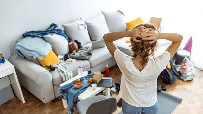 woman looking at cluttered couch