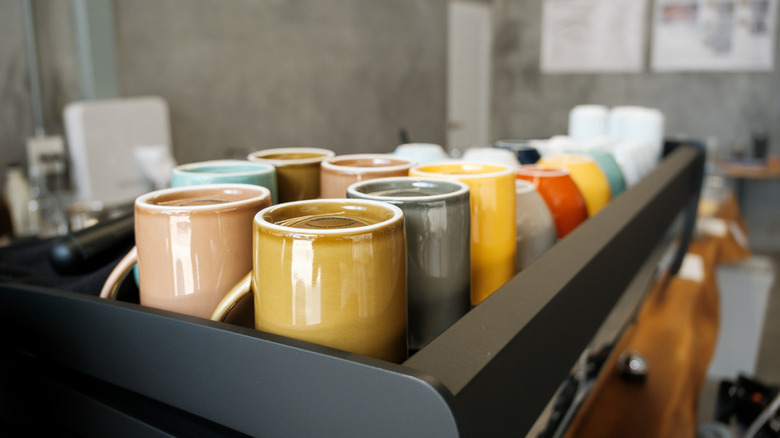 Colorful coffee mugs placed upside down in tray