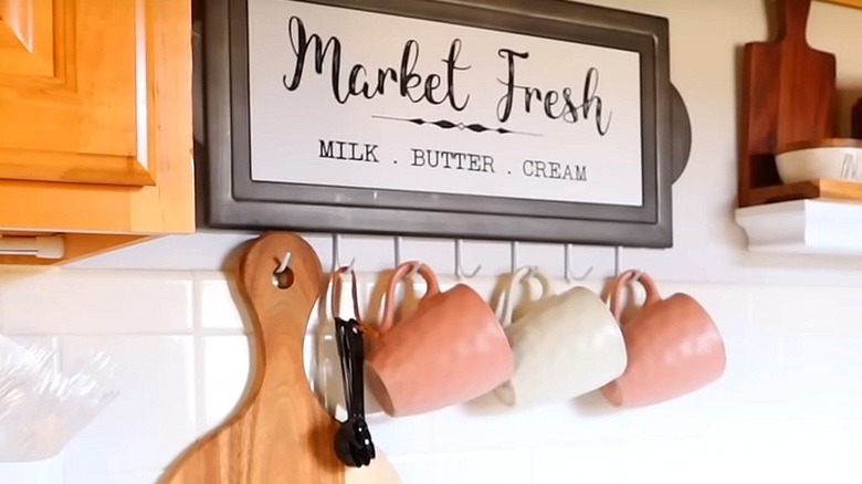 Coffee mugs hanging from hooks installed on kitchen wall