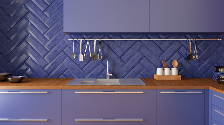 Purple color-drenched kitchen with herringbone tile backsplash.