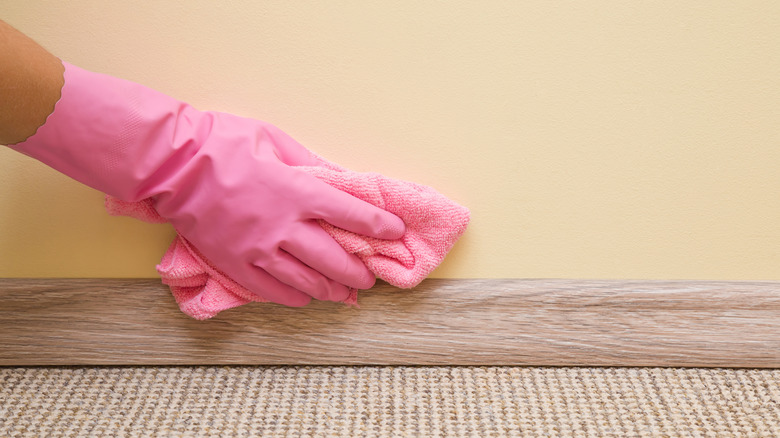 Person wearing rubber glove scrubbing wall