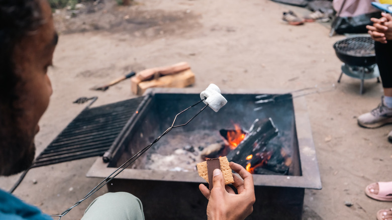 man making s'more by firepit