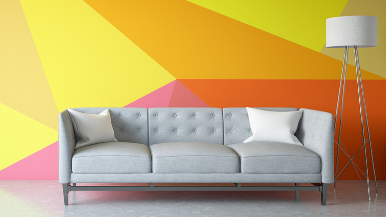 Gray couch with a vibrant color-blocked wall in the background