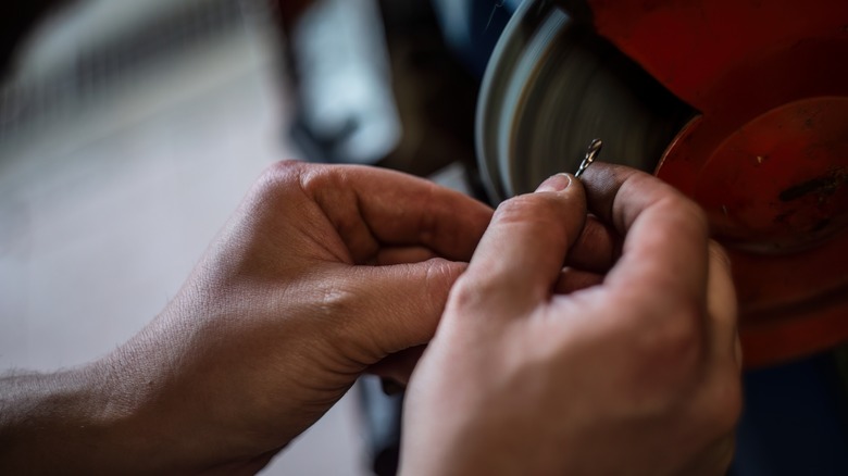 hands holding drill bit to sharpen