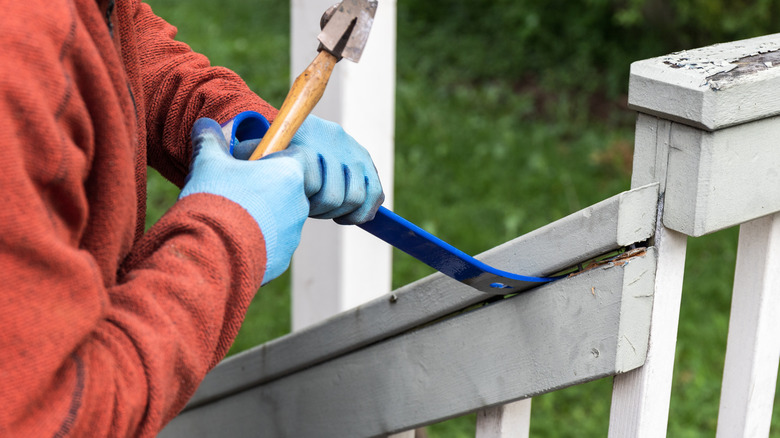 man using pry bar on outdoor stair railing