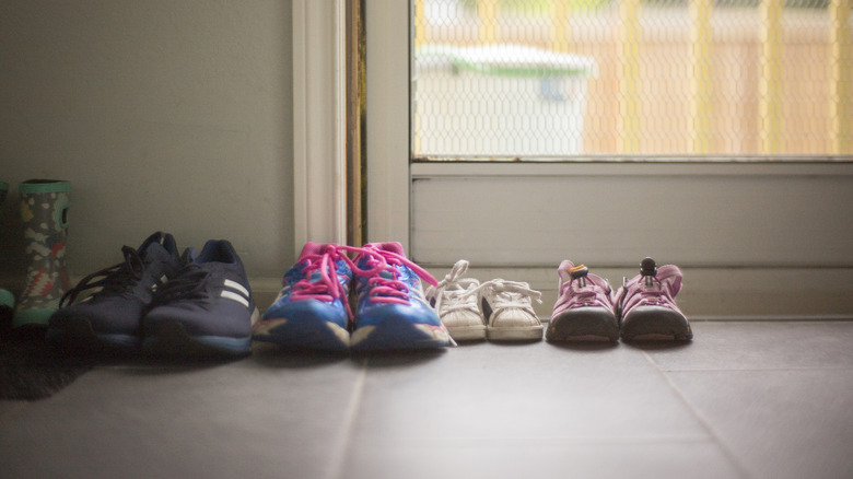 multiple sneakers sitting by sliding door in home