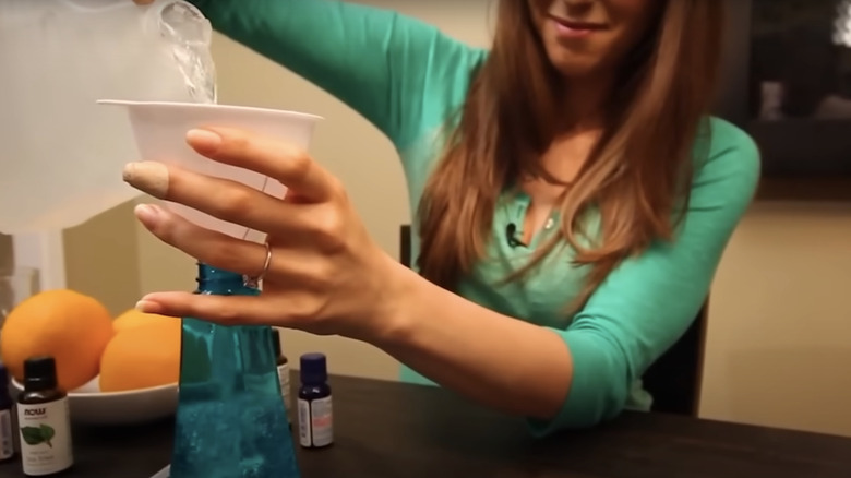 woman pouring white vinegar in spray bottle