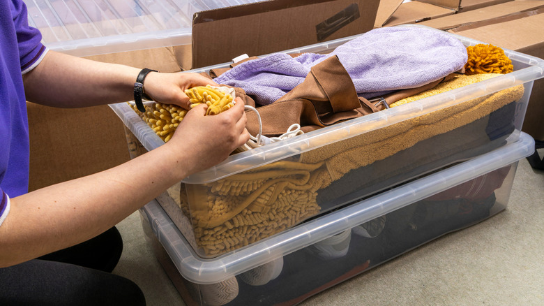 Person storing clothing items in plastic bins