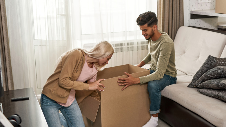 A couple puts unknown object into a cardboard box