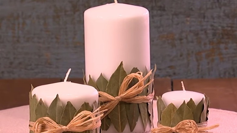 White candles wrapped with bay leaves and raffia bow.