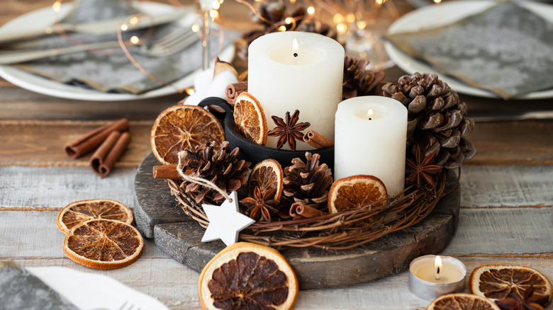 centerpiece with. candles, pinecones, cinnamon, and orange slices