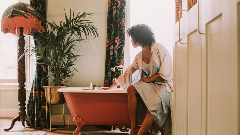 A woman sits in a bathroom with pink and green décor