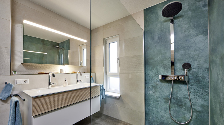 A neutral bathroom features blue accent towels and blue walls in the shower