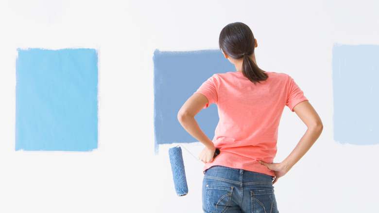 Woman looking at blue paint on wall