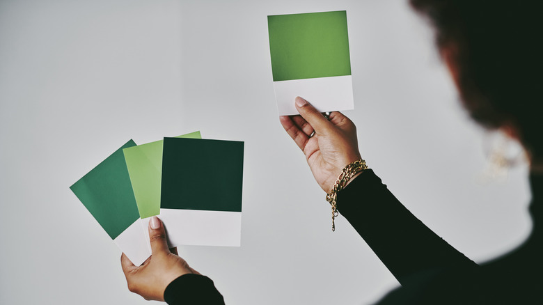 person holding green paint swatches