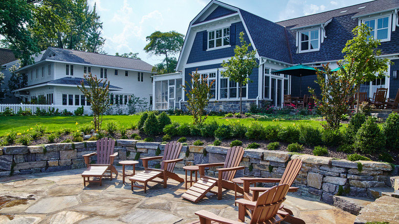 Blue barnstyle home with a front patio and retaining wall