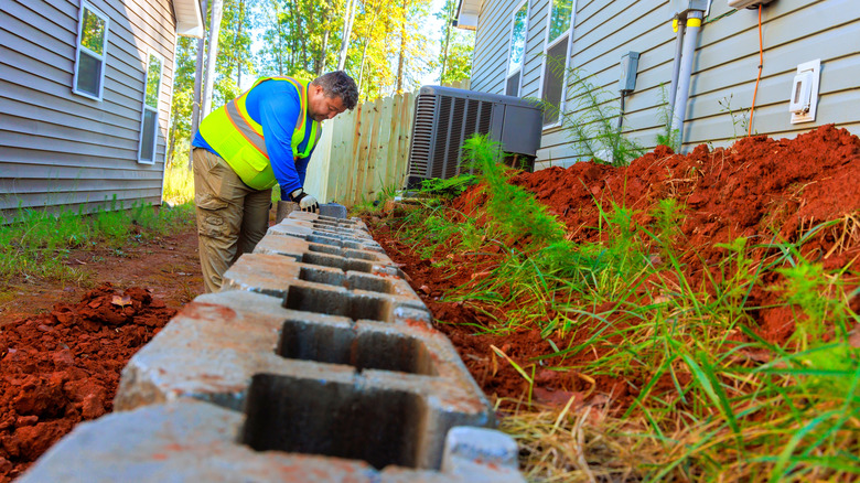 Worker building a retaining wall beside a home