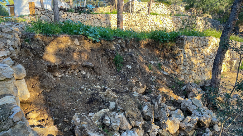 Collapsed stone retaining wall with rocks and stones