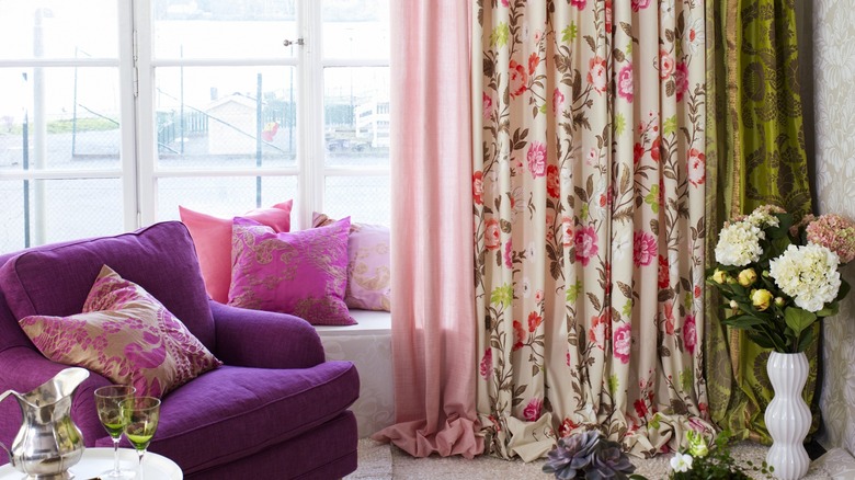 Purple sofa near window with colorful curtains and pillows