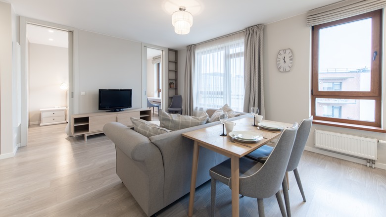 Apartment living room with gray furniture, shades, and curtains