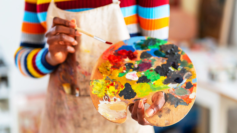 person holding color palette and brush