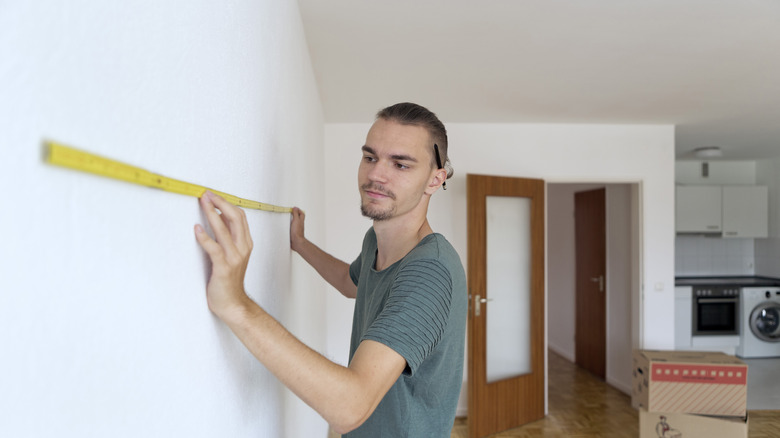 Person measuring a wall