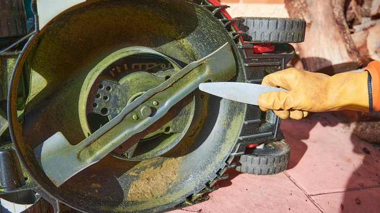 person sharpening mower blades