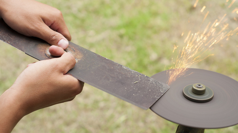 person sharpening mower blade