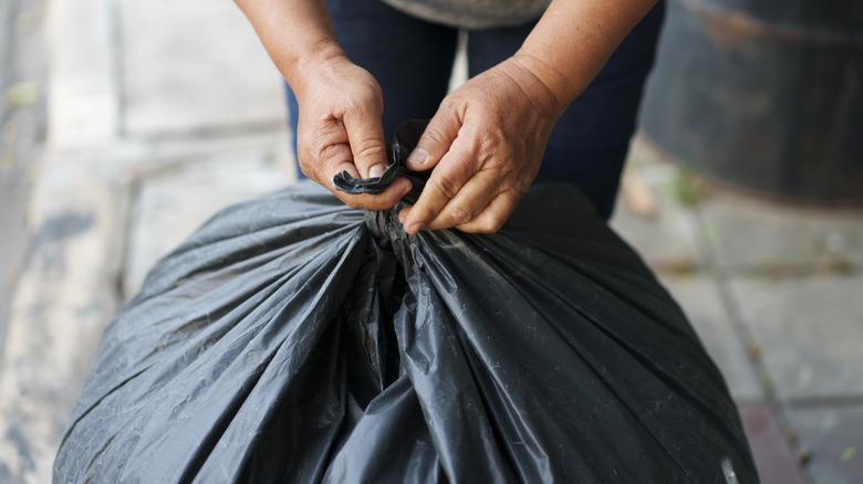 person holding tied trash bag