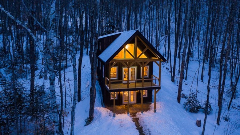 Lit up cabin in snow and woods