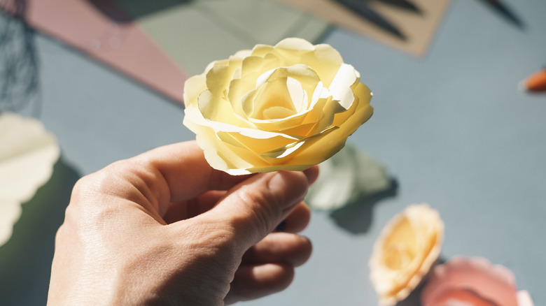 Hand holding paper yellow rose