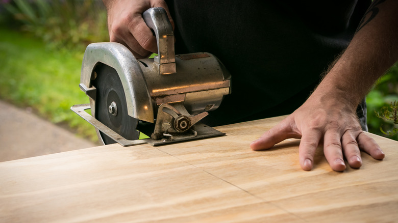 person sawing plywood
