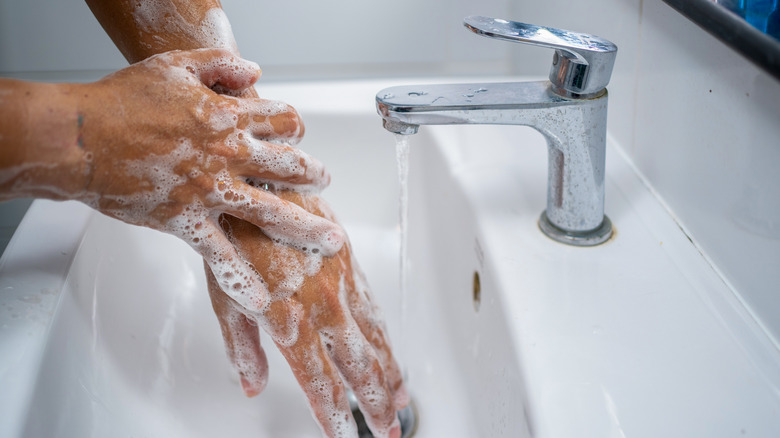 A person washing their soapy hands in the sink