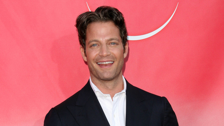 Nate Berkus smiles in front of a red wall