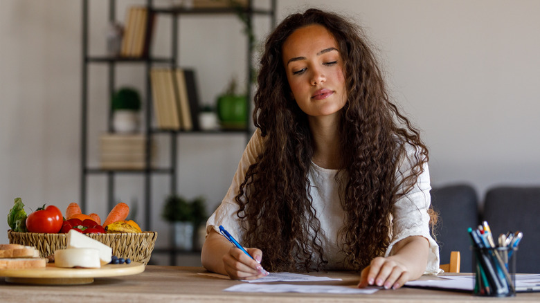 woman writing out meal plan