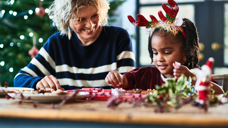 Women and little girl making homemade Christmas decorations