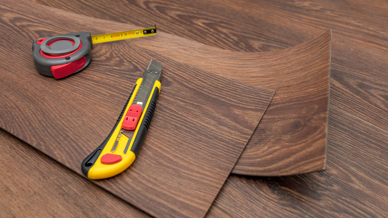 A tape measure and utility knife used to install peel and stick vinyl flooring