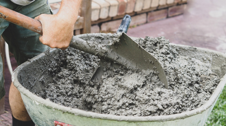 A man mixing concrete by hand in a wheelbarrow