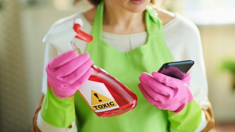 Woman holding toxic cleaner bottle