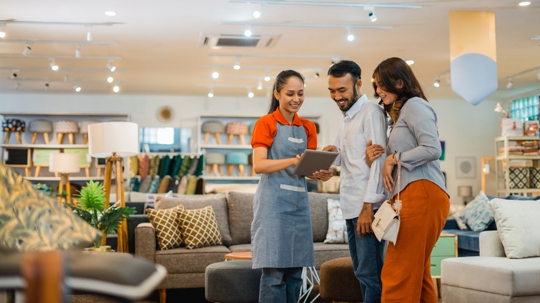 female furniture store employee assisting husband and wife