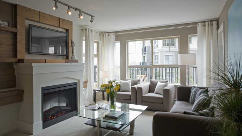 A glass coffee table is surrounded by sofa chairs in a living room