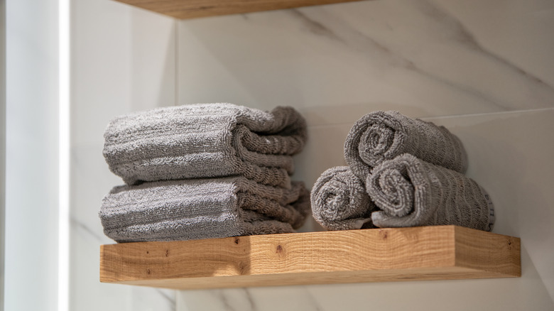 Neatly rolled hand towels on a wooden shelf